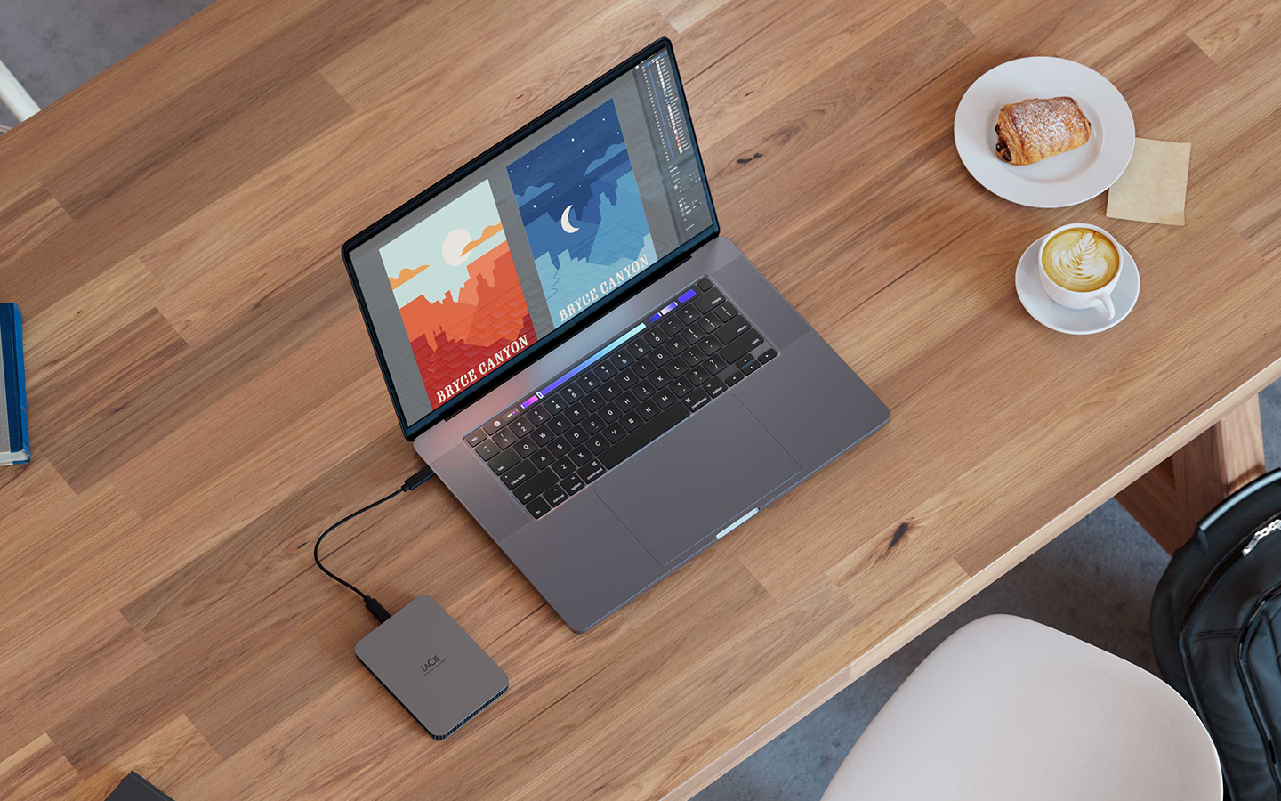 Overhead image of a laptop connected to a Seagate mini external drive sits next to a coffee and pastry, indicating working on the go.