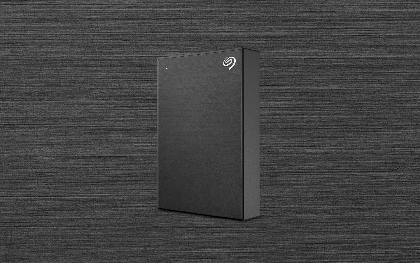 Seagate Backup Plus portable drive in black is standing in front of a textured background.