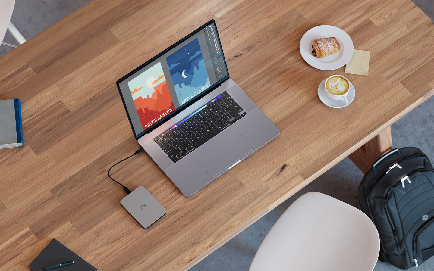 Image of a laptop connected to a LaCie Mobile Drive Secure sits next to a coffee and pastry, indicating working on the go.