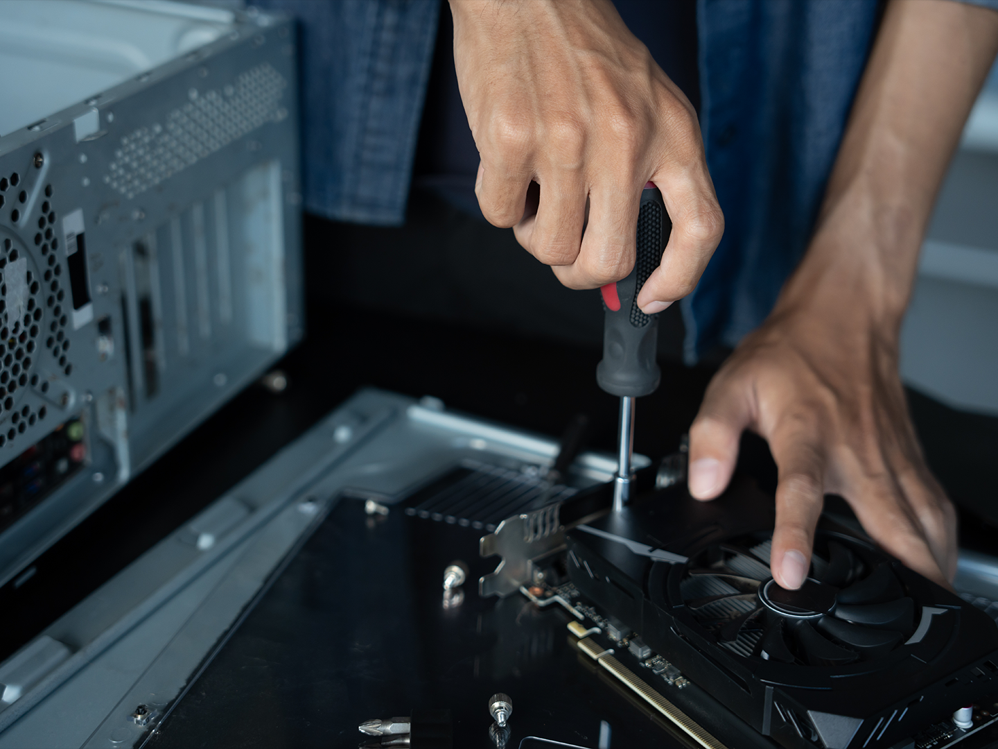 Person working on a hard drive is shown using a screwdriver to secure a component.