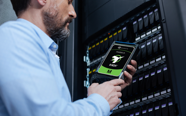 Person holds a drive featuring Seagate, Mozaic 3+, and Exos logos, to install in a data center rack.