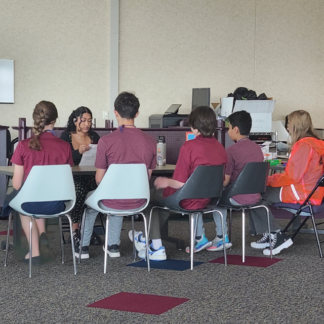 A Seagate employee mentor and five high school students meet at a small table.