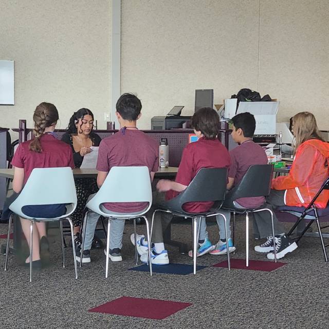 A Seagate employee mentor and five high school students meet at a small table.