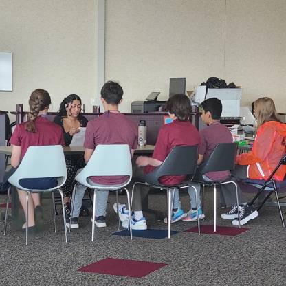 A Seagate employee mentor and five high school students meet at a small table.