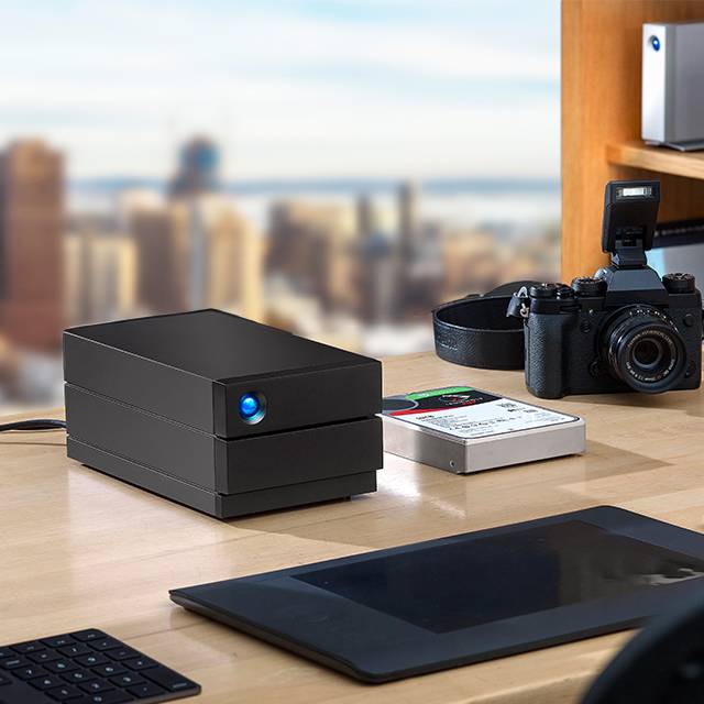 Close-up of LaCie 2big RAID and portable SSD sit next to an SLR camera.