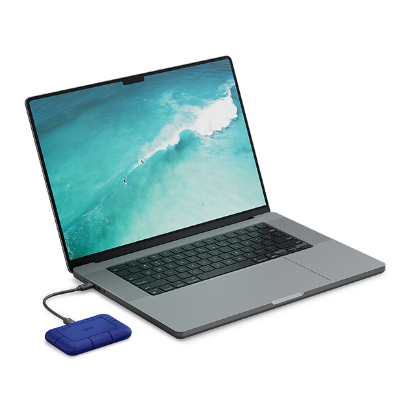 A LaCie Rugged Pro5 drive is shown plugged into a laptop.