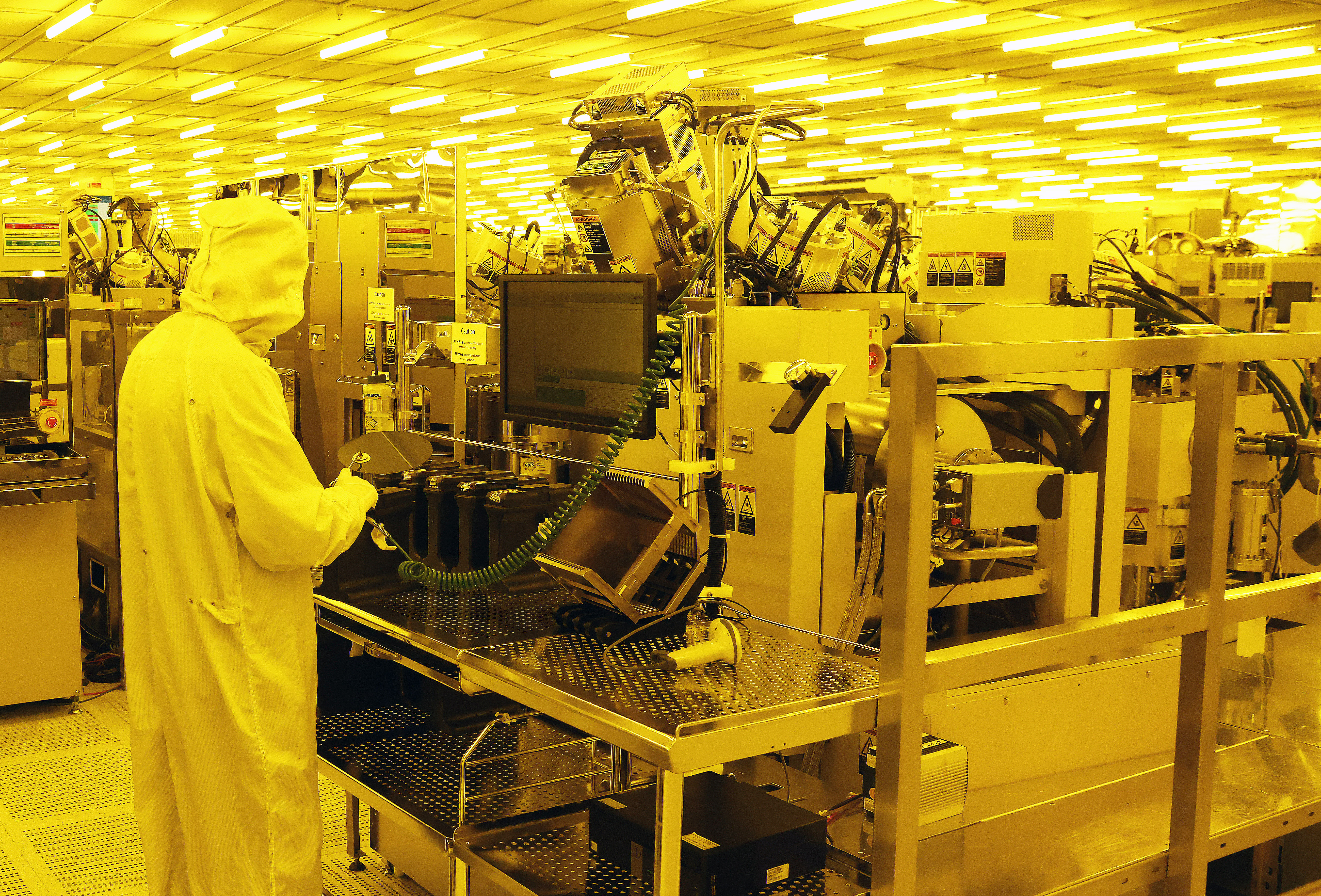 Person in a cleanroom wearing protective gear works with electronic equipment in a Northern Ireland manufacturing facility. 
