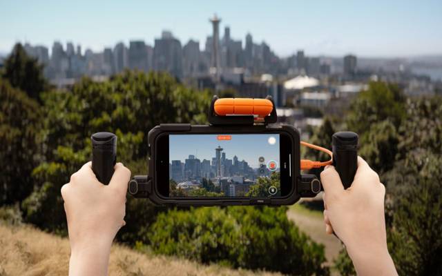 Person filming skyline with phone on stabilizer; LaCie Rugged SSD4 plugged in.