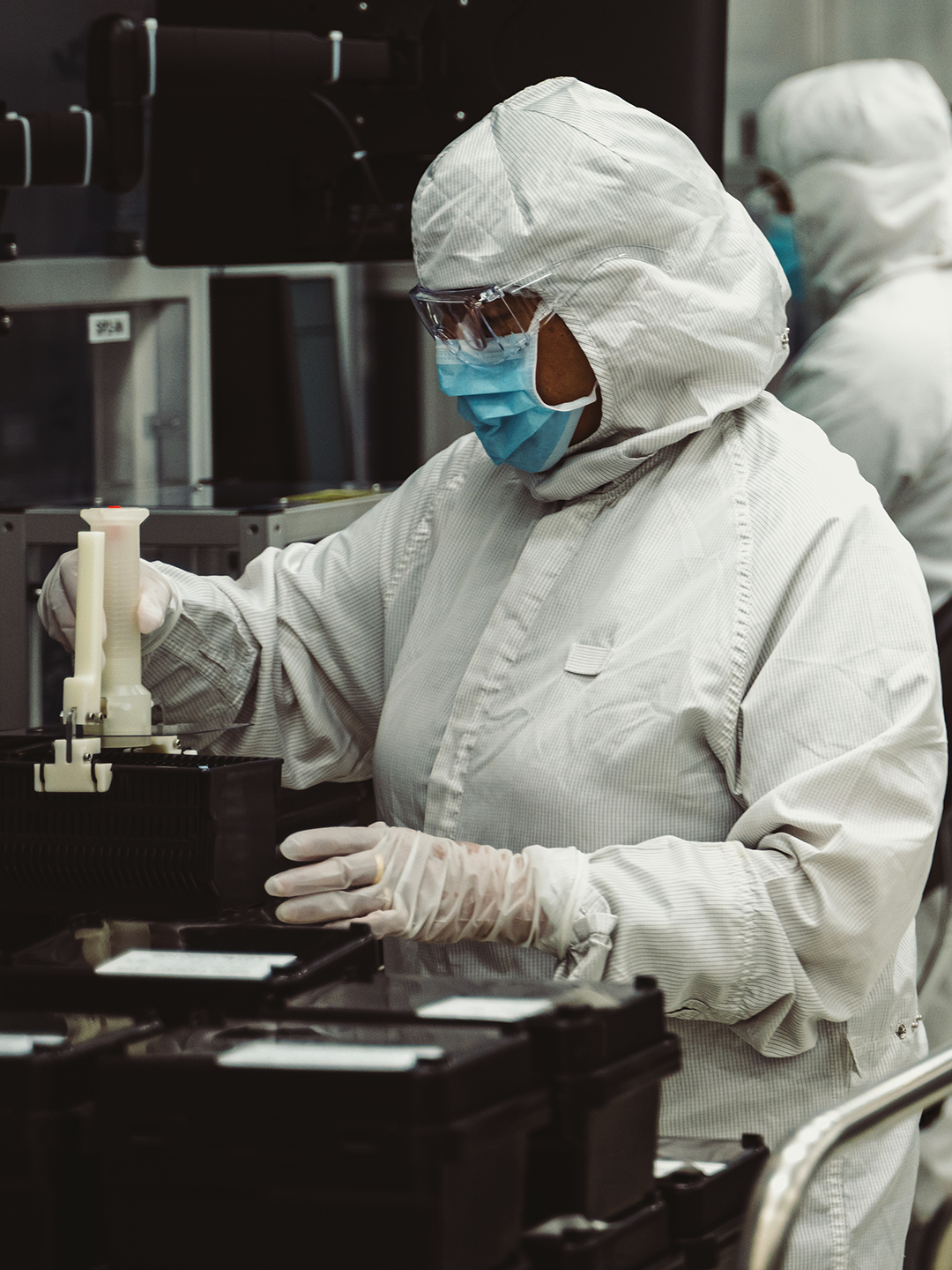 身着全套洁净室防护服的人员正在操作技术组件。